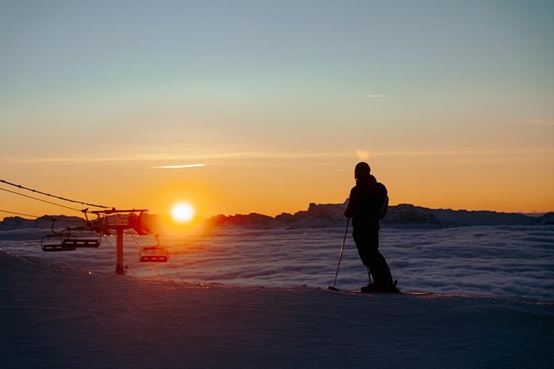 Photo d'un skieur devant le coucher de soleil et la mer de nuages